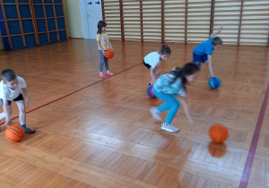 Dzieci toczą piłkę do koszykówki.